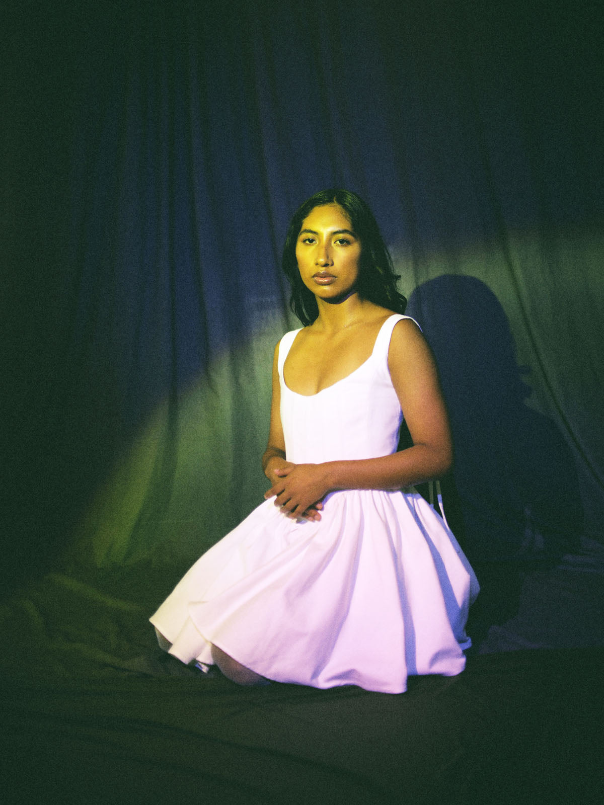 model sitting down with white cotton corset dress with gathered skirt and ribbon lace-up details by Mariana by Alba