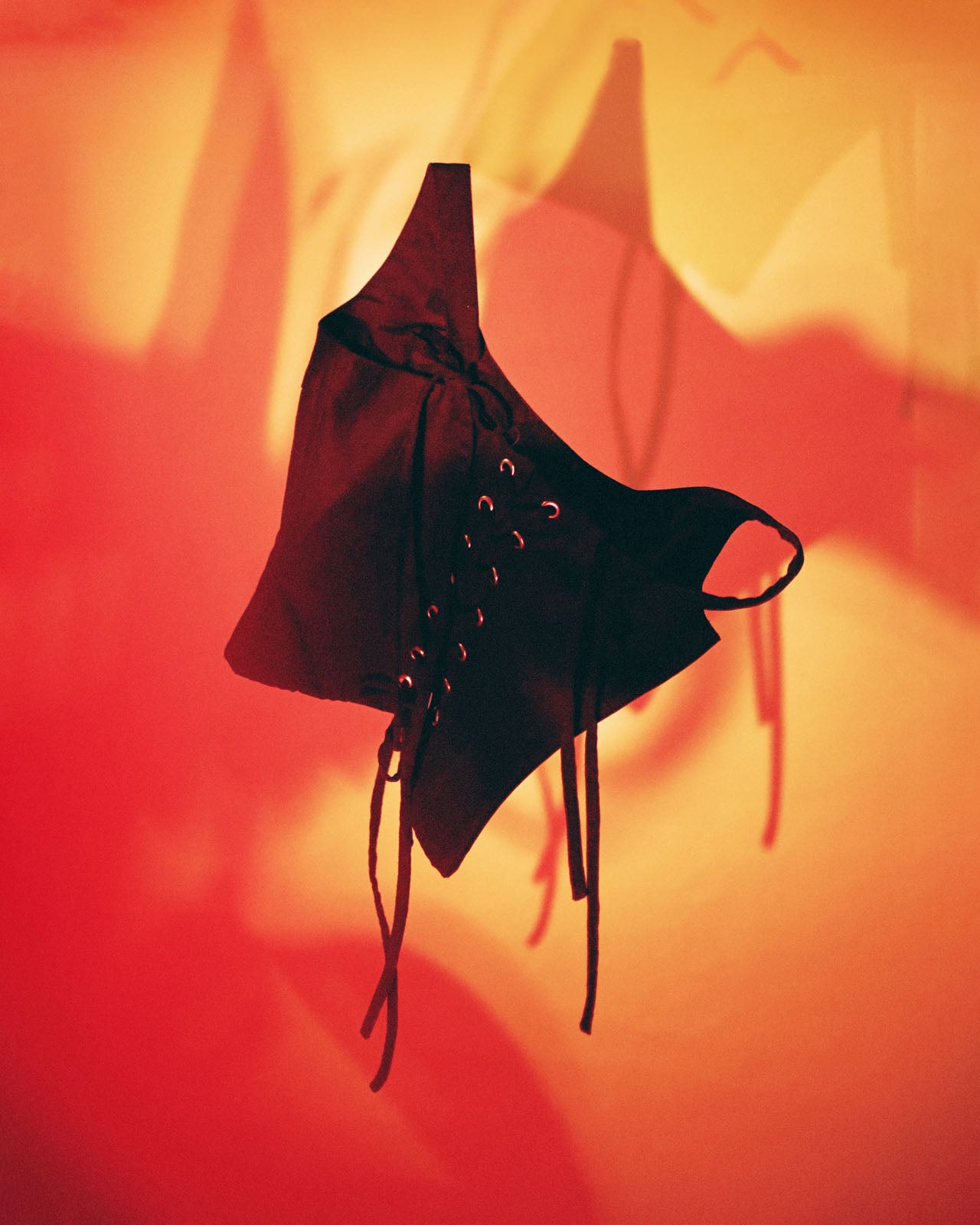 Black lace-up boot against a red and orange gradient background