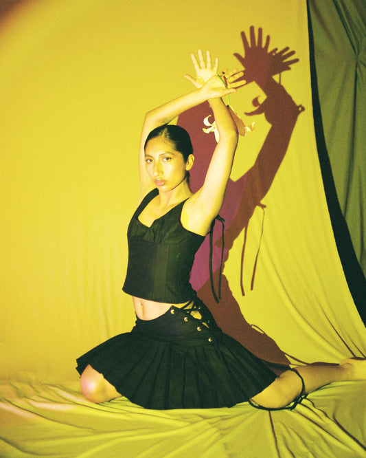 model dancing with black cotton corset top with scoop neckline and adjustable ribbon ties by Mariana by Alba.